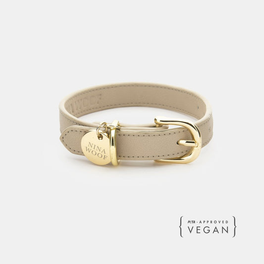 Beige Copenhagen Dog Collar made with PETA-approved vegan leather with gold reinforced hardware and Nina Woof tag on a white background