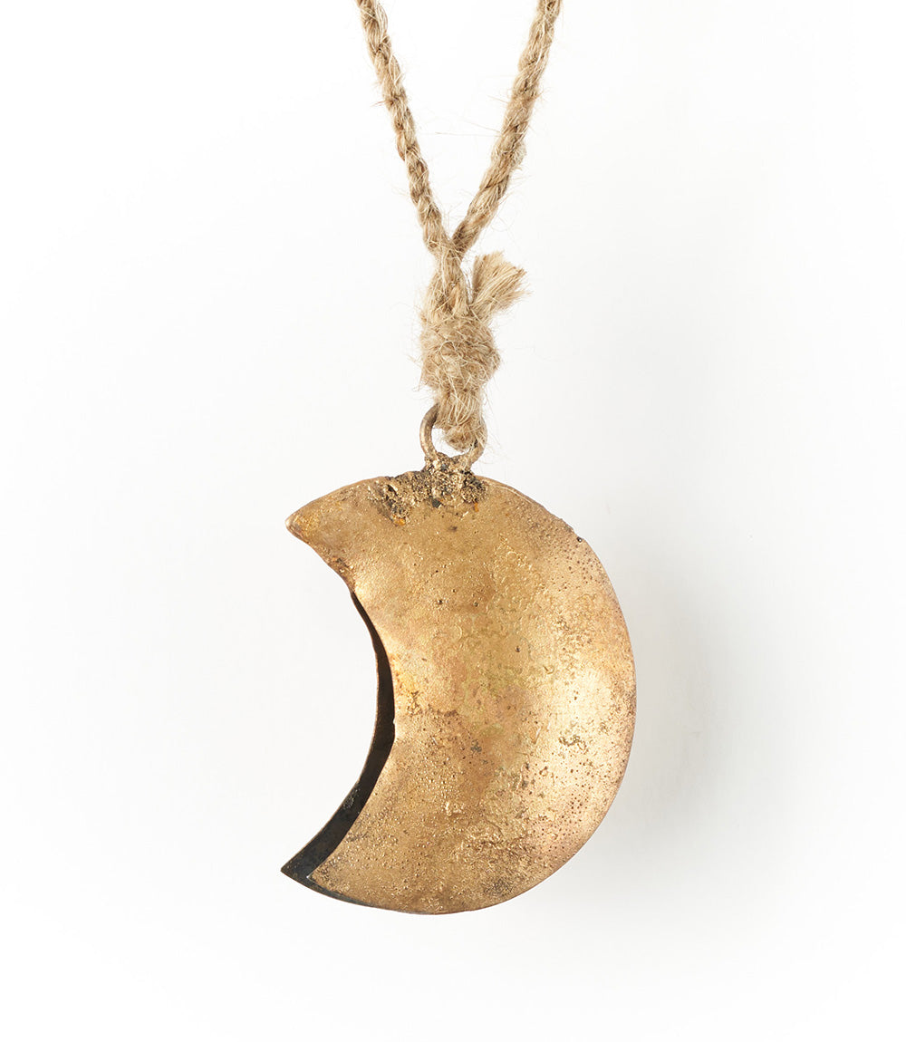 A bronze crescent moon wind chime with a rustic bell, hanging from a jute rope.