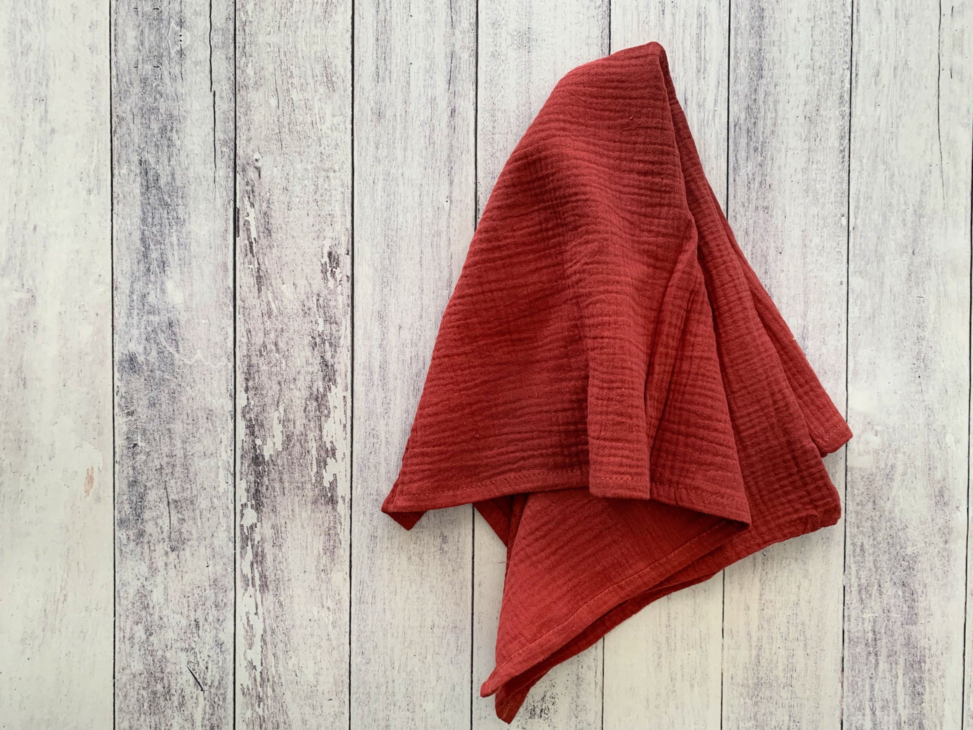 Brick 100% cotton dinner napkin from Dot and Army, arranged on a wooden surface