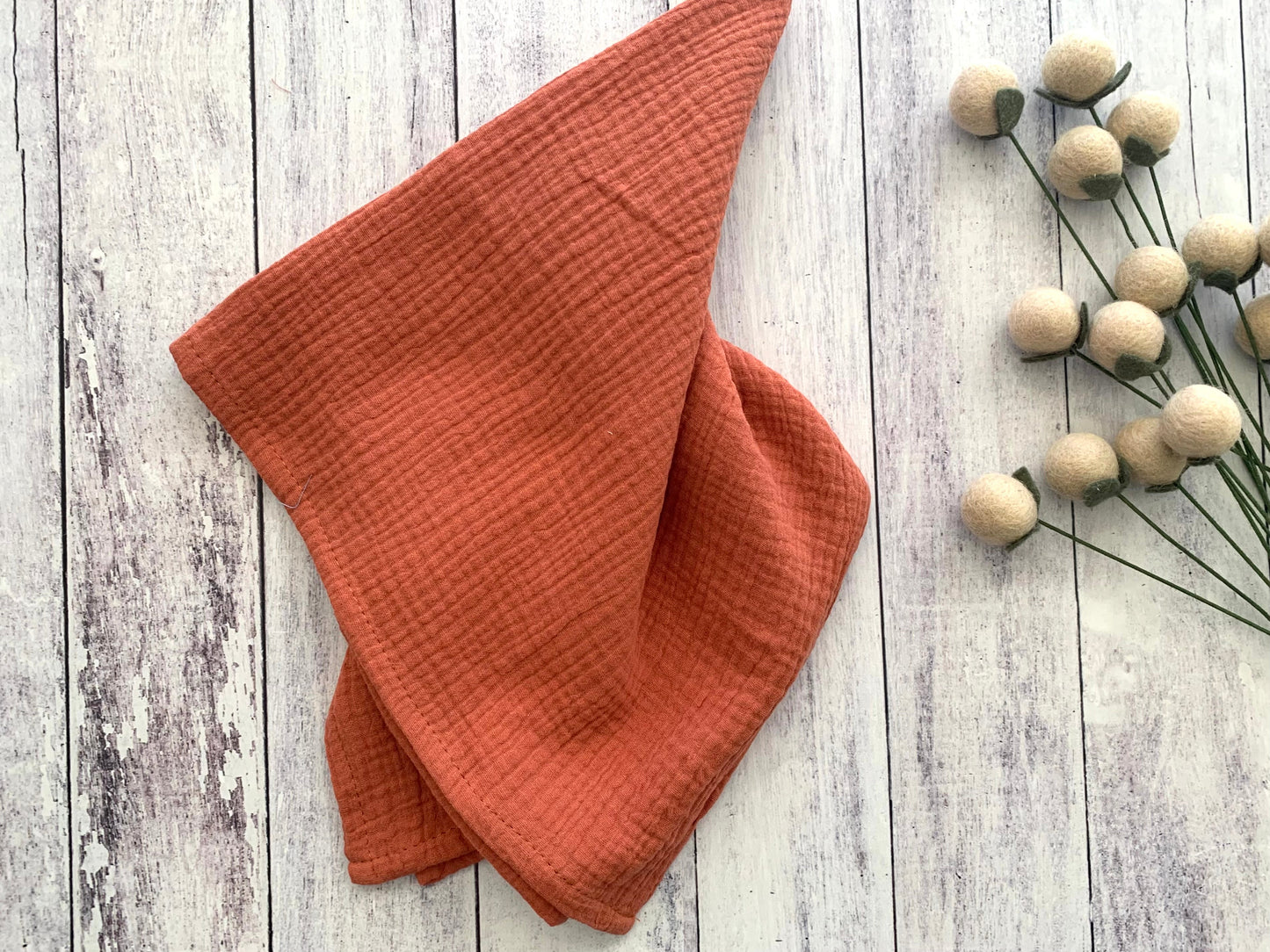 Burnt Orange 100% cotton dinner napkin from Dot and Army, arranged on a wooden surface
