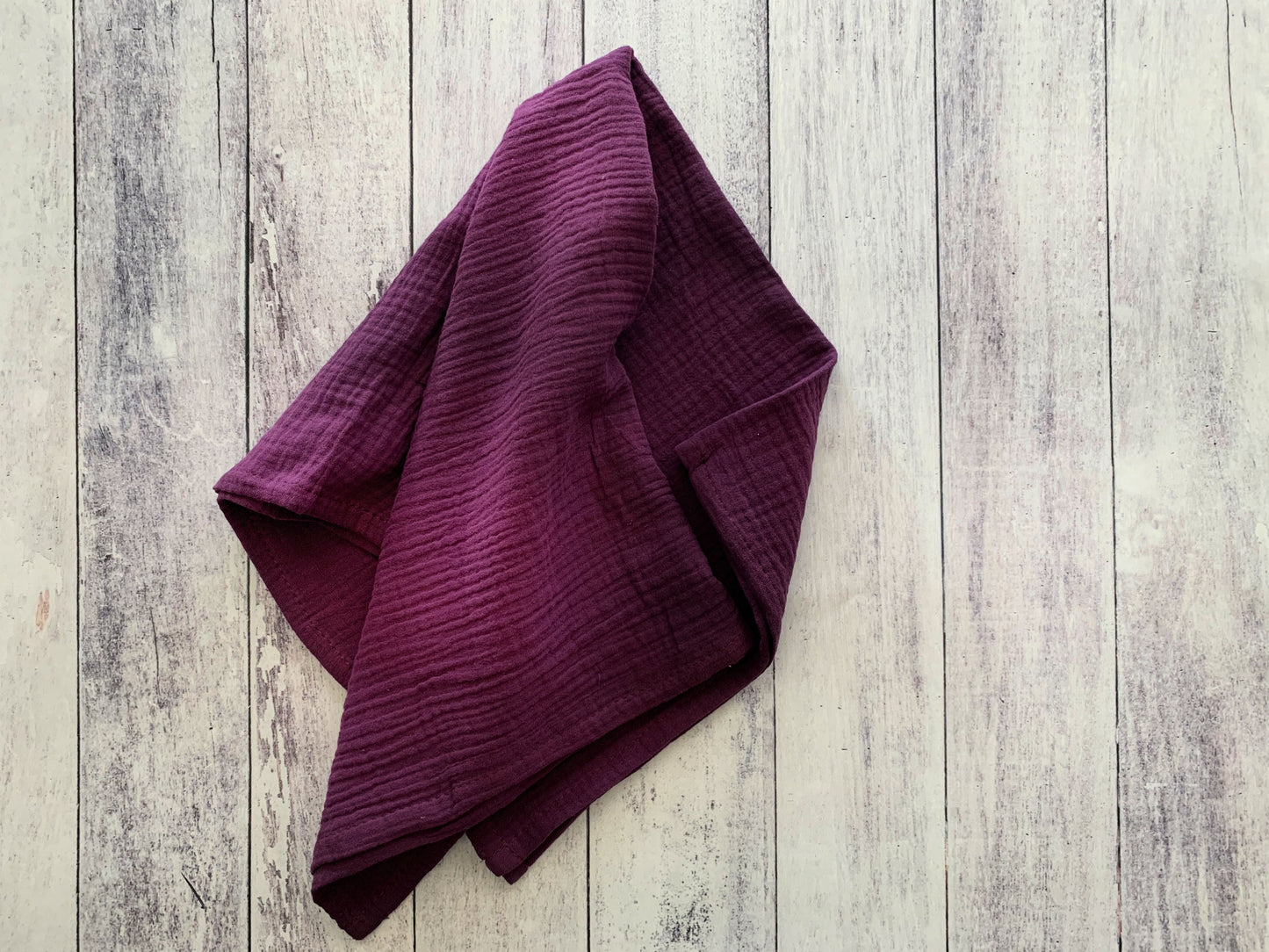 Eggplant 100% cotton dinner napkin from Dot and Army, arranged on a wooden surface
