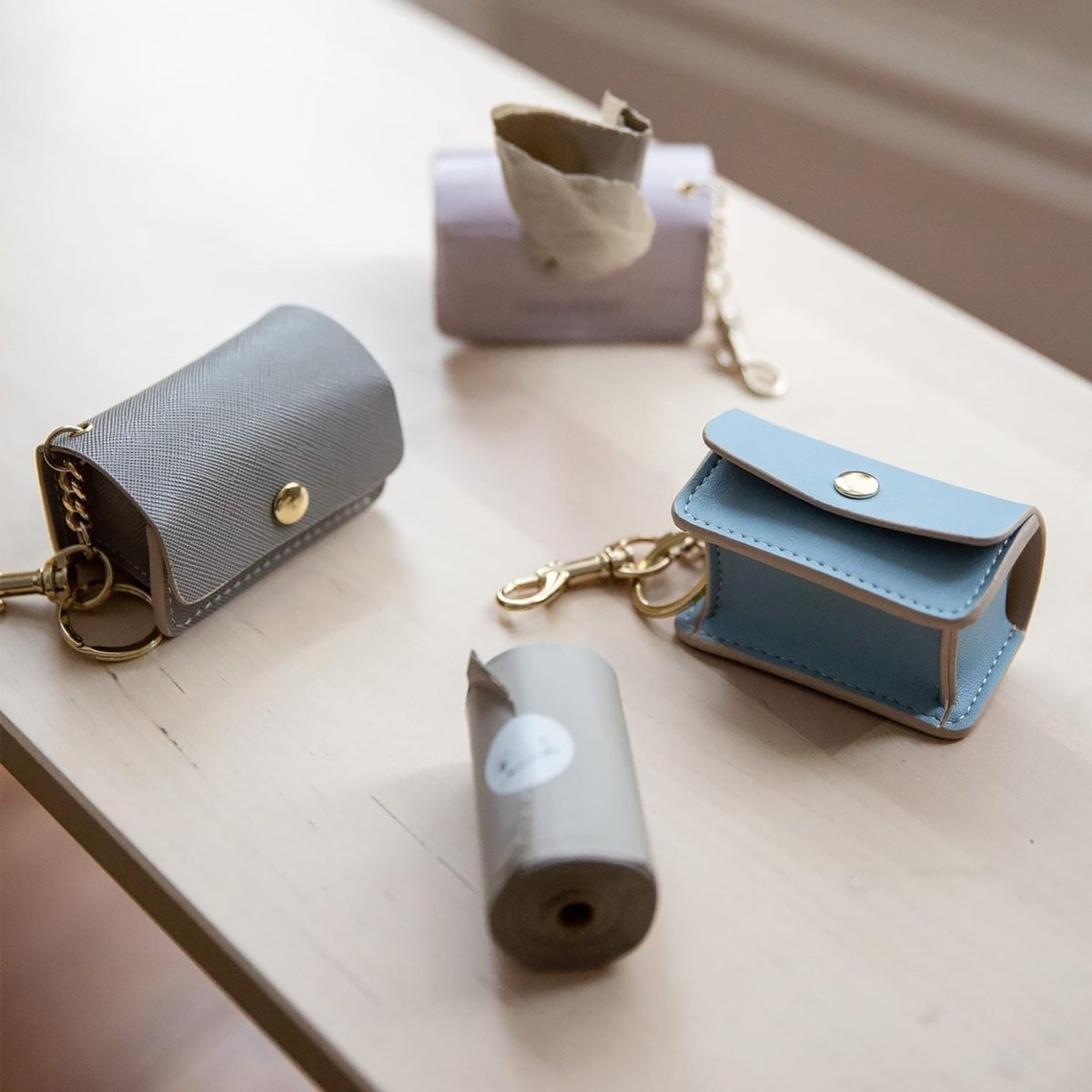 Nina Woof vegan leather dog waste bag holders in a variety of colors on a light wooden surface