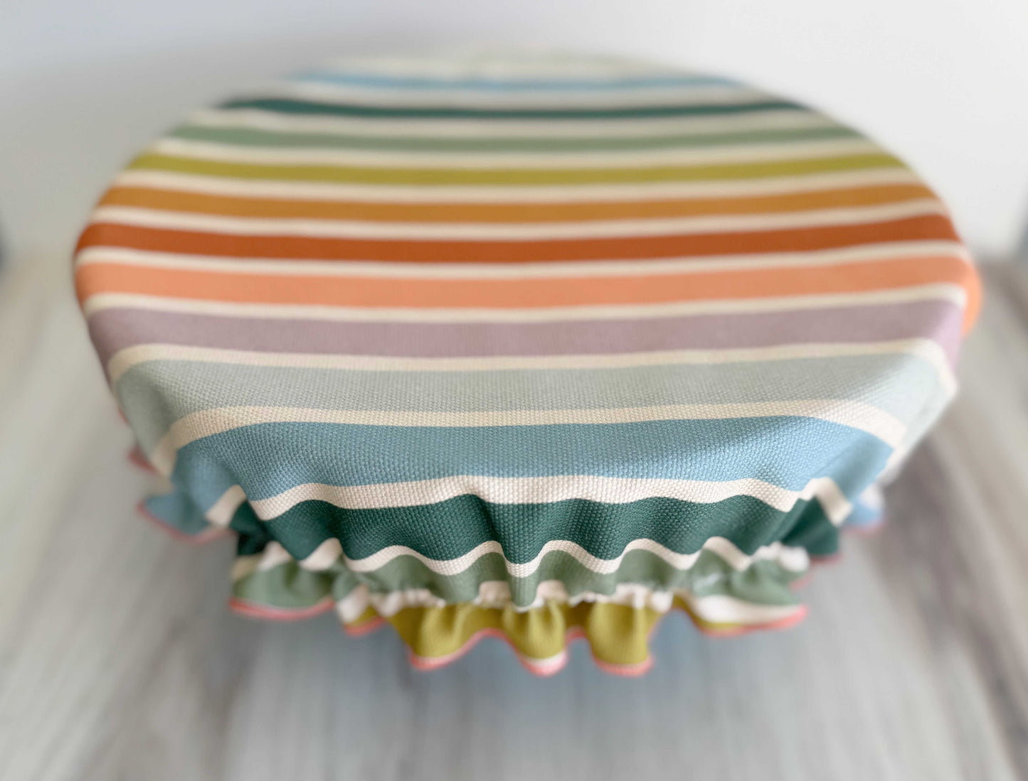 Colorful striped, plastic-free, reusable bowl cover by Dot & Army covering a bowl on a white counter