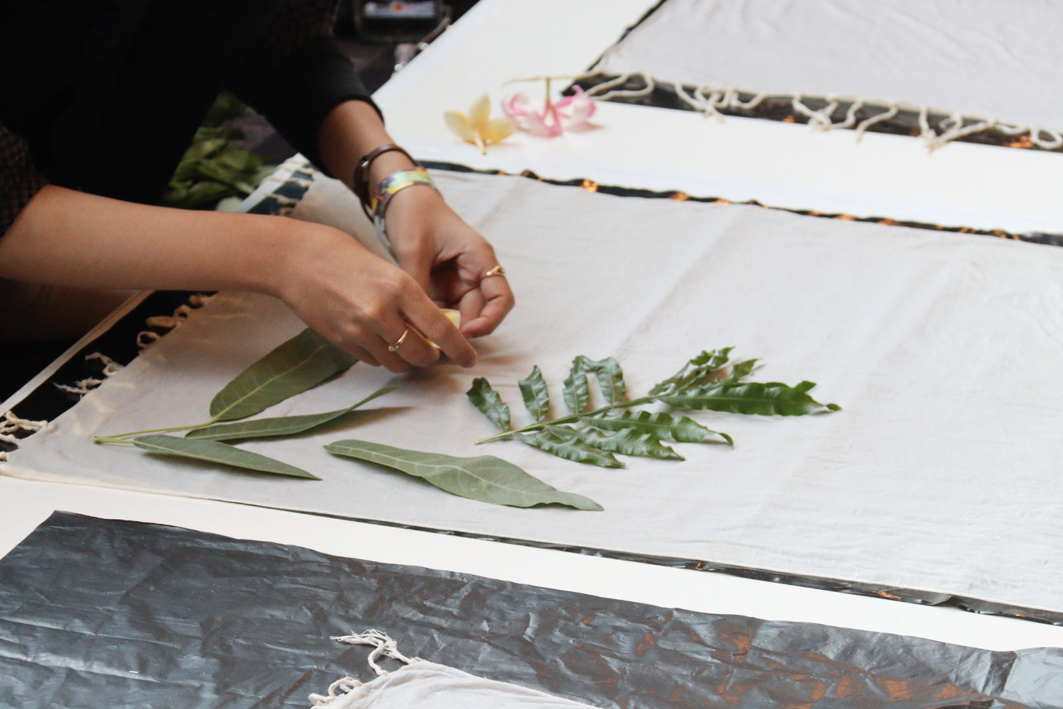 Woman arranging leaves on textile for eco-printing, showcasing natural dyeing and sustainable textile techniques.