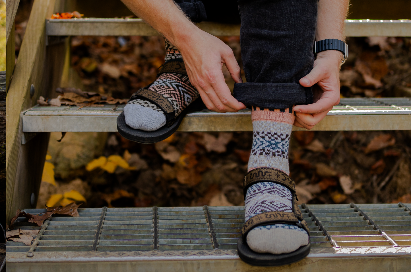 Person sitting on steps in sandals wearing patterned Madrona socks by Solmate, made with a blend of recycled merino wool, with a natural outdoor background.