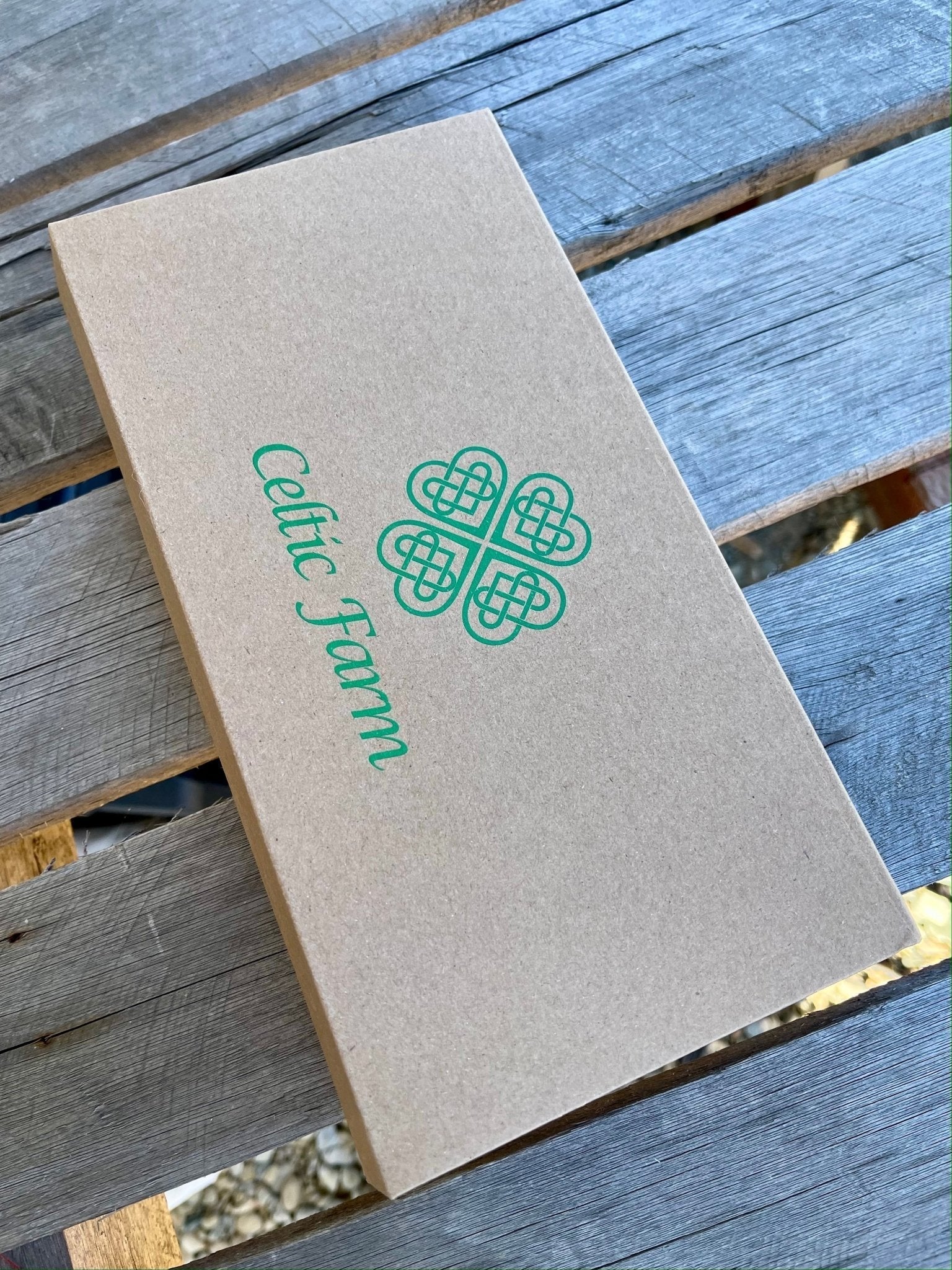 Brown cardboard gift box with 'Celtic Farm' logo on a wooden surface