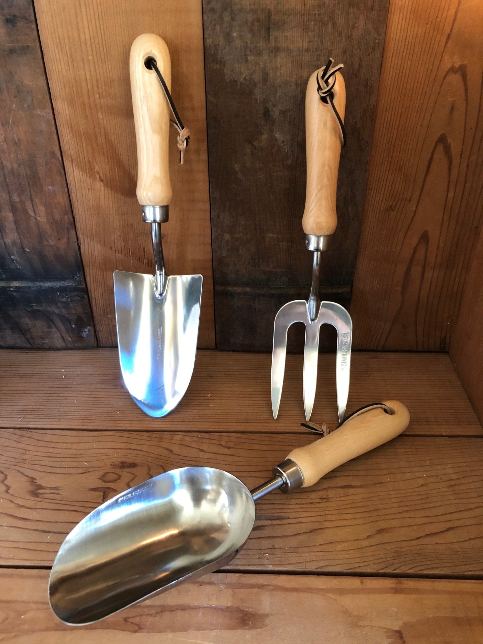 Three gardening tools with wooden handles on a wooden surface
