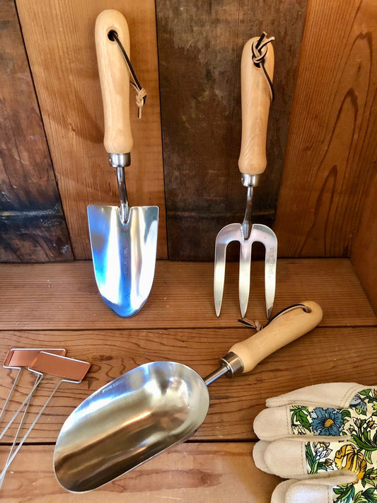 Set of gardening tools with wooden handles and stainless steel on a wooden surface