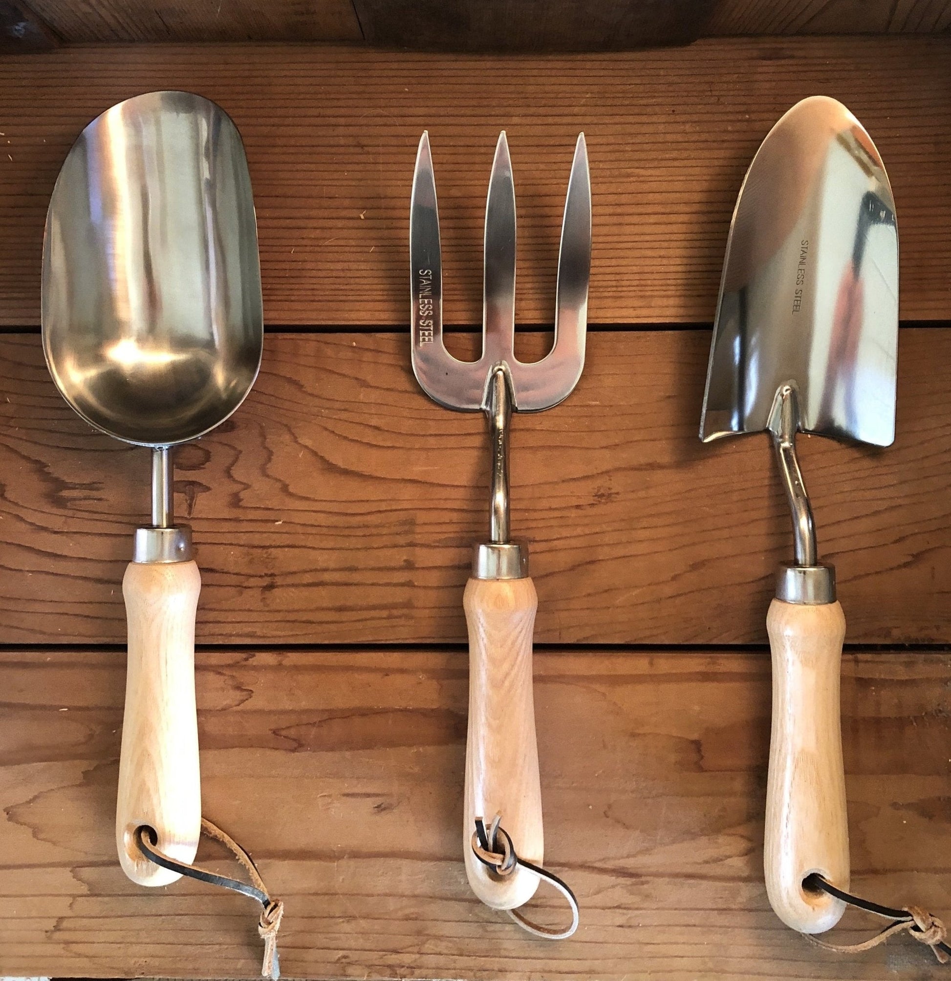 Set of three gardening tools with wooden handles on a wooden background
