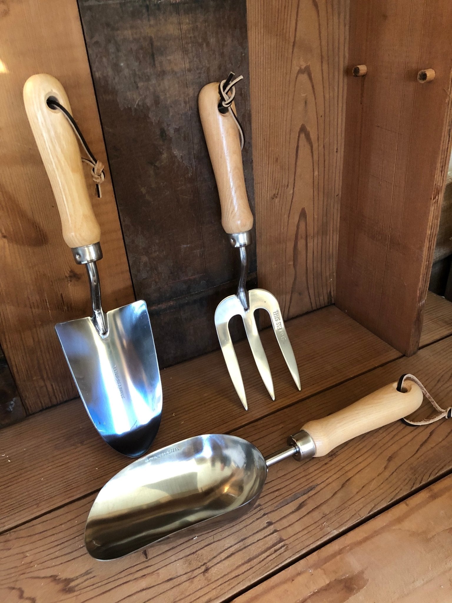Set of gardening tools with wooden handles on a wooden surface