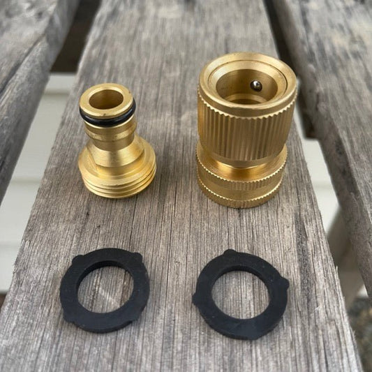 Two brass hose connectors and two black washers on a wooden surface