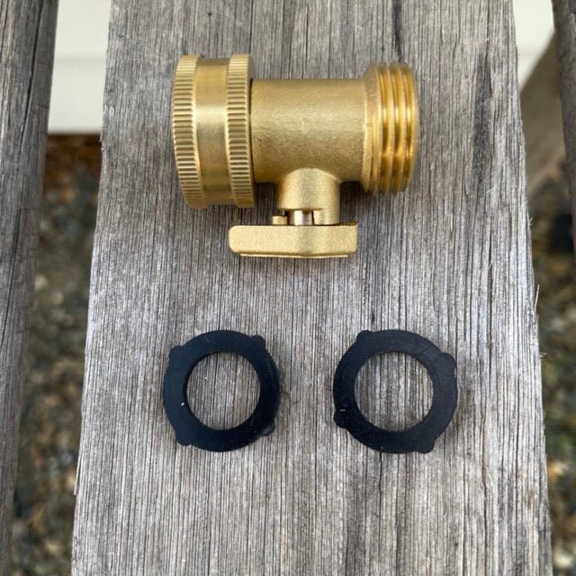 Brass shut-off hose valve and two black washers on a wooden surface