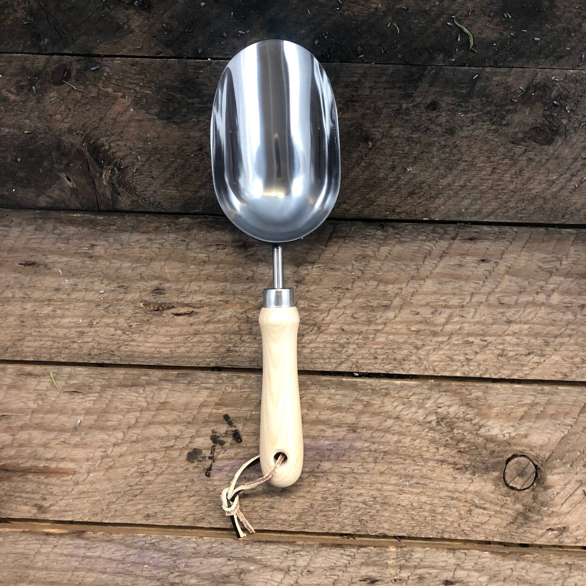 Metal garden shovel with a wooden handle on a wooden background