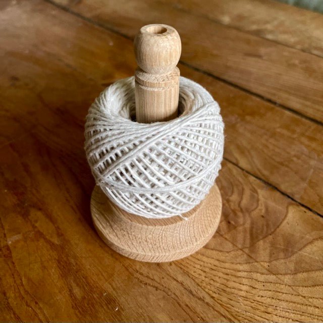 Oak spool with white twine on a wooden surface