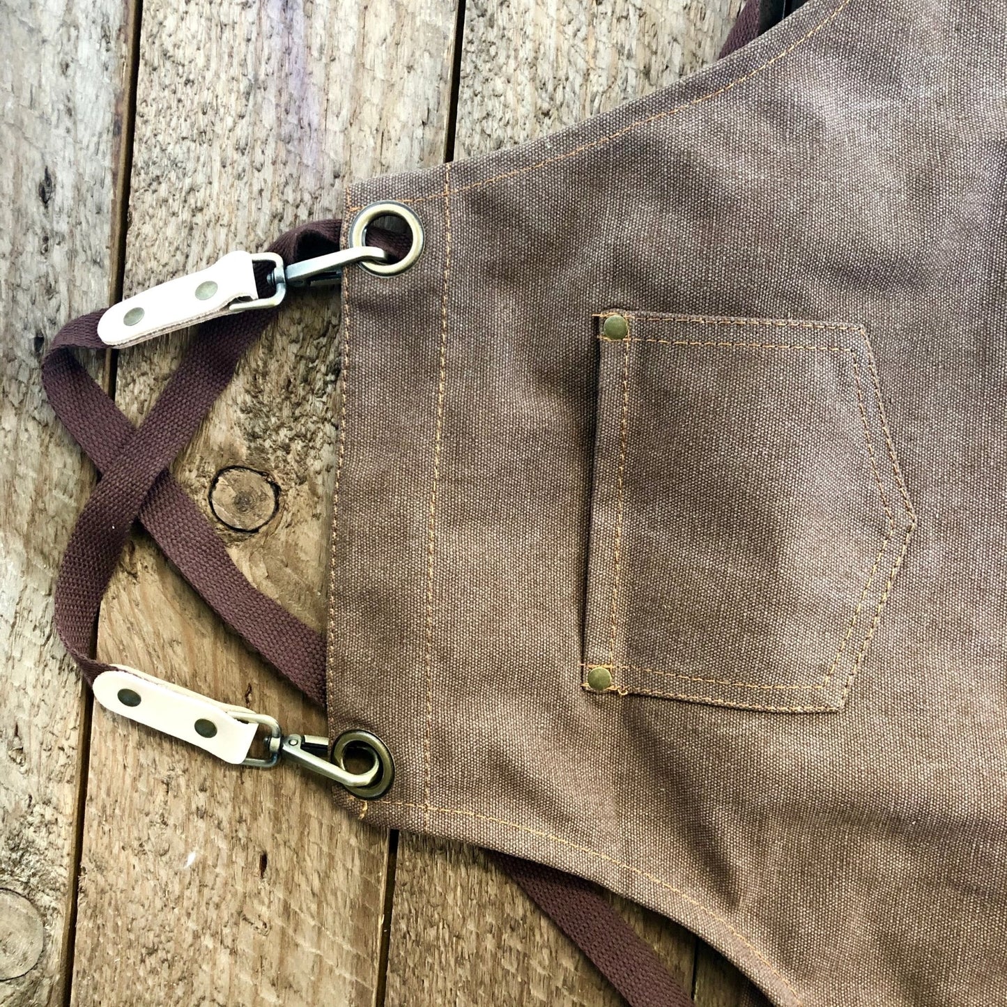 Brown florist apron with a pocket and straps on a wooden surface