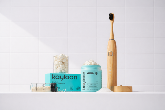 Kaylaan Bamboo Electric Toothbrush next to blue and white containers on a white surface with a light gray background