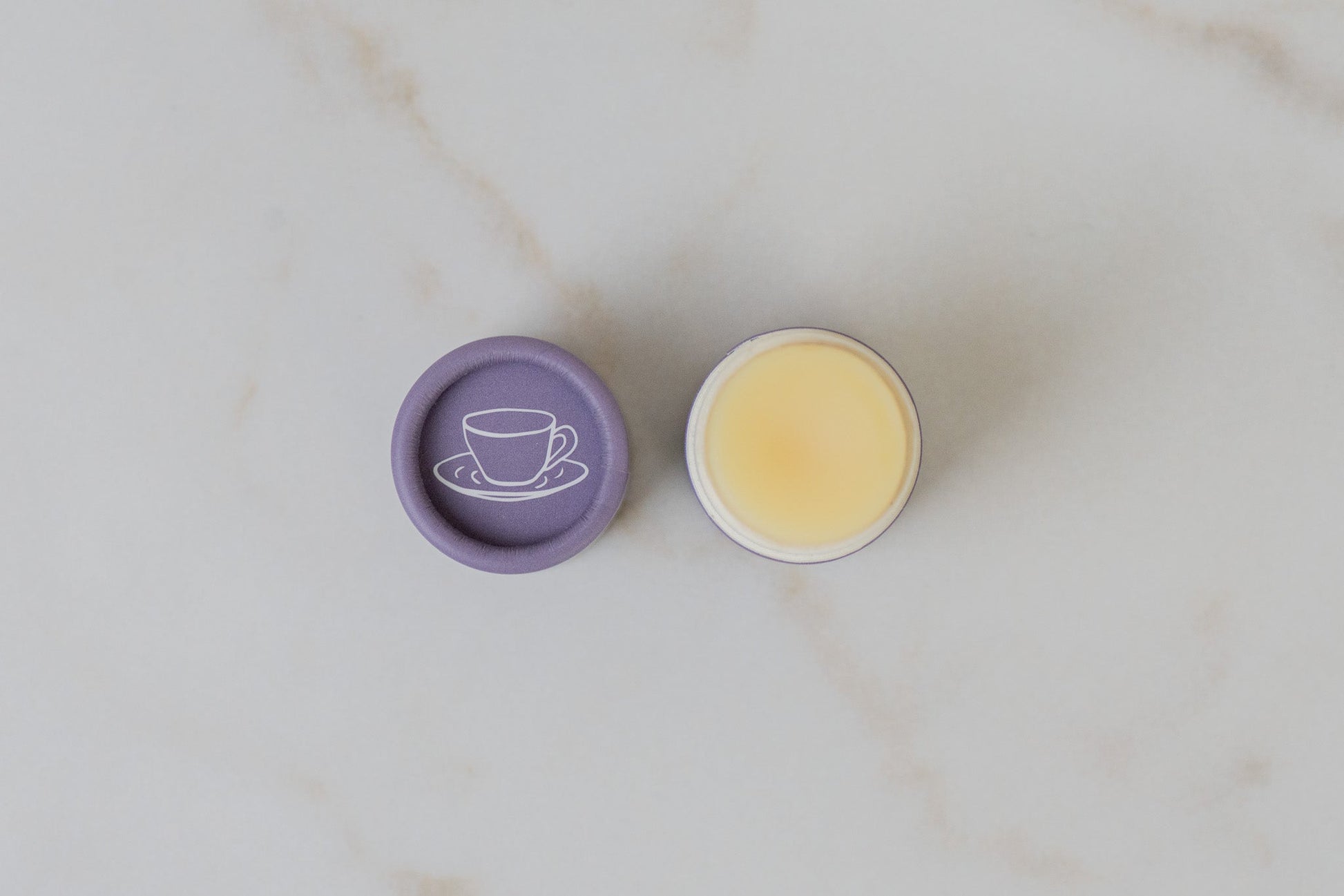 Open tube of No Tox Life SolidSilk Lavender Earl Grey Lip Balm on a marble surface.