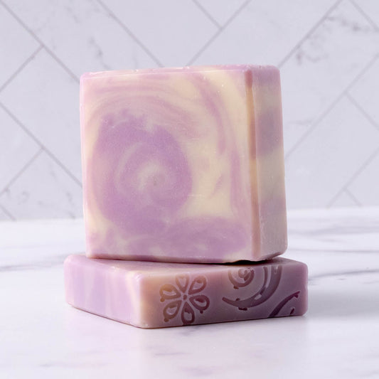 Two bars of purple and white lavender soap with a floral design on a white background