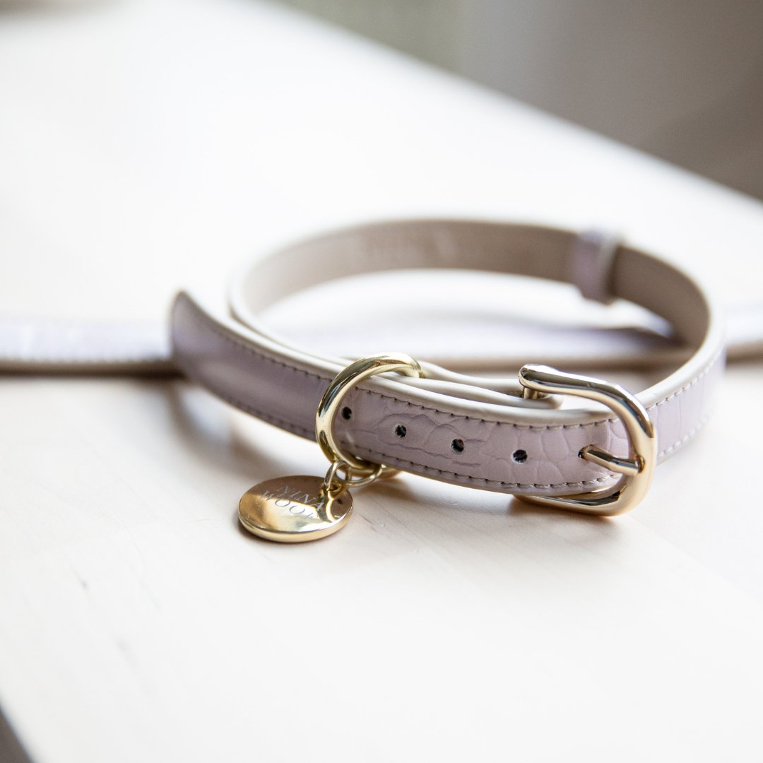 Lilac Nina Woof Vegan Leather dog collar with gold hardware on a white surface