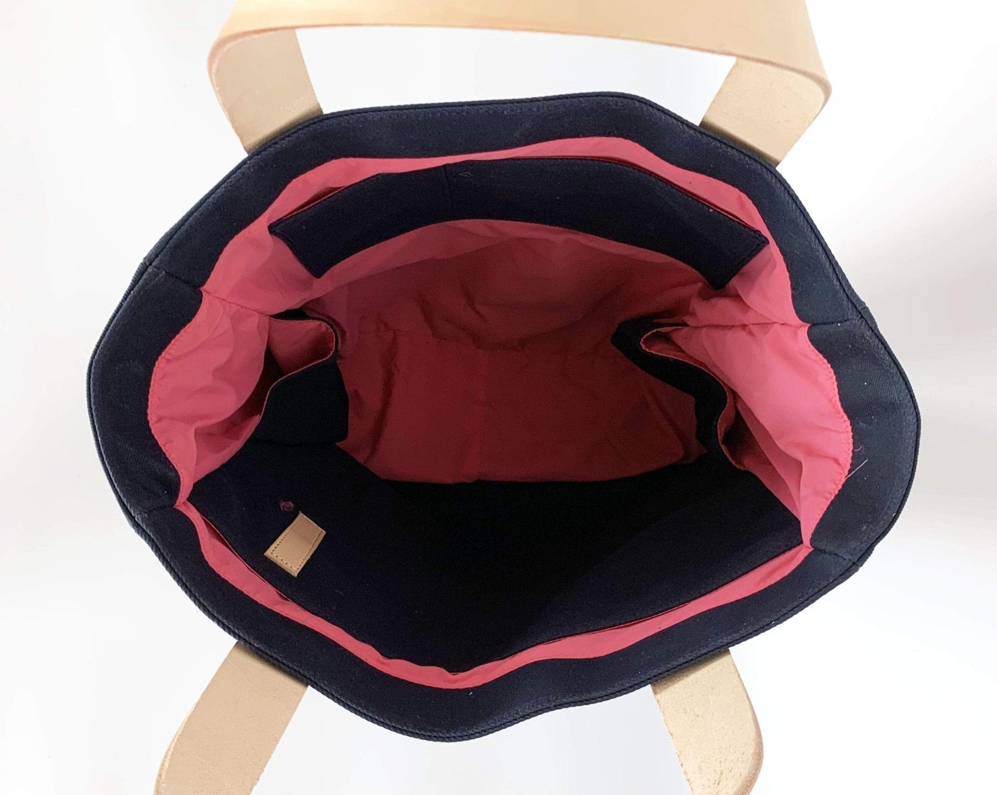 Inside view of the Waxed Canvas Tote Bag – Navy with Bright Pink Lining, Durable & Eco-Friendly, on a wooden stool with a white background