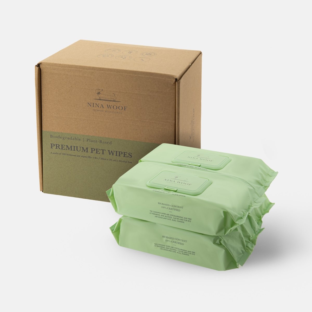 A cardboard case of Nina Woof premium biodegradable pet wipes and four green packages of sustainable wipes beside it on a white background