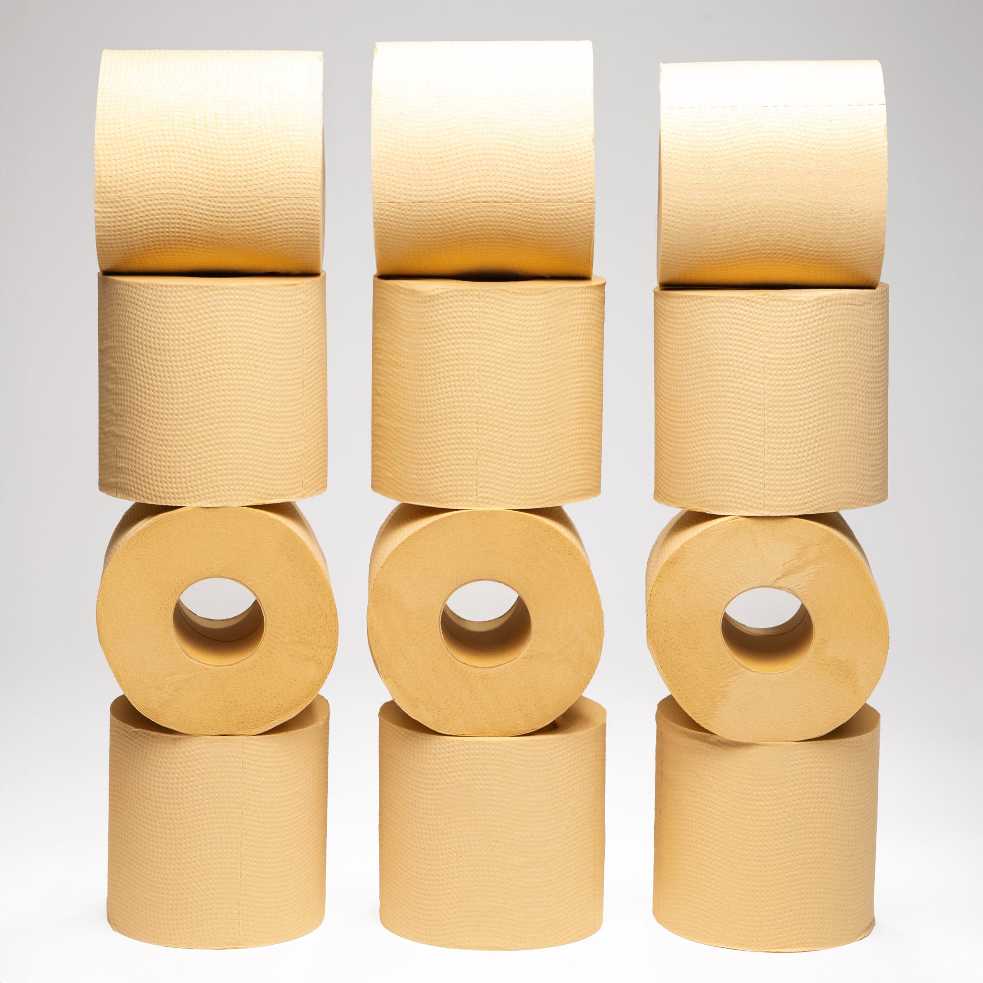 Stacks of beige Panda Eco Paper Bamboo Toilet Paper rolls on a light gray background