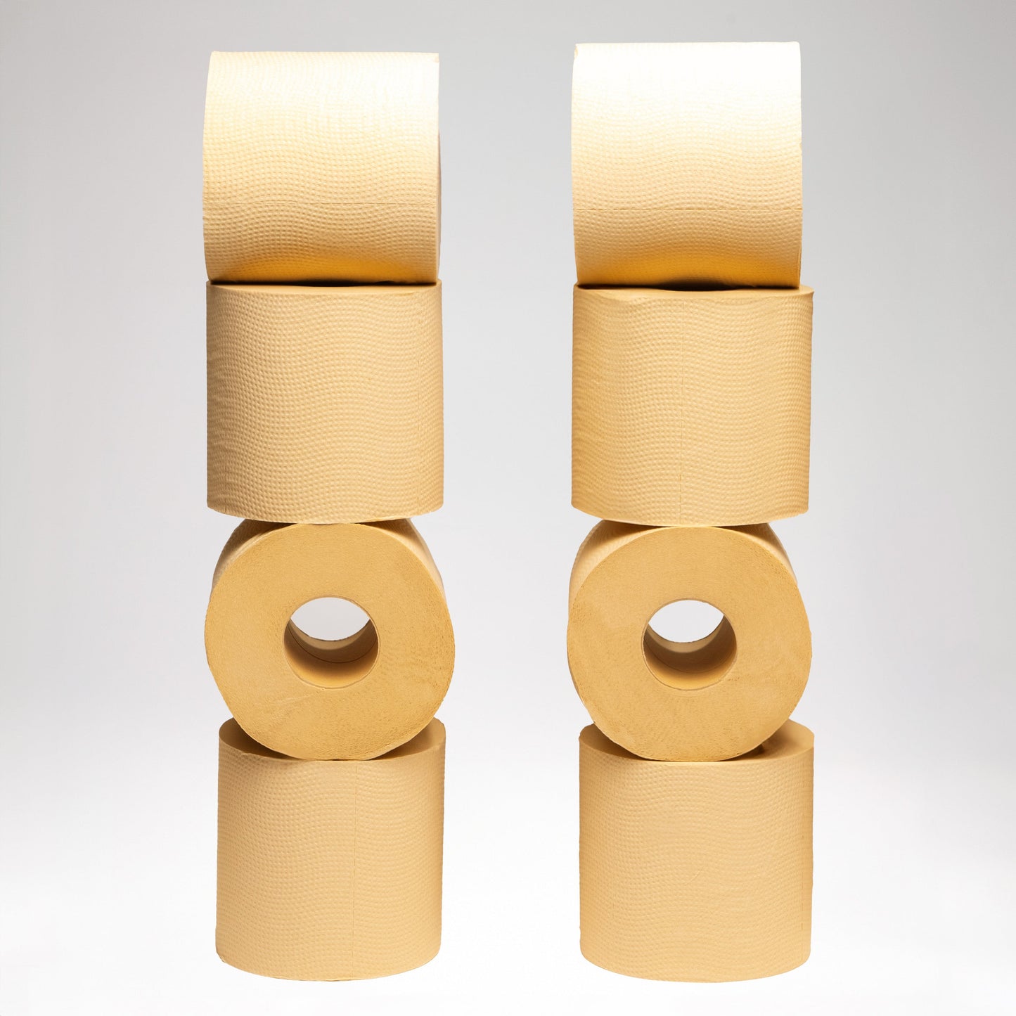 Stack of beige Panda Eco Paper Bamboo Toilet Paper rolls on a light gray background