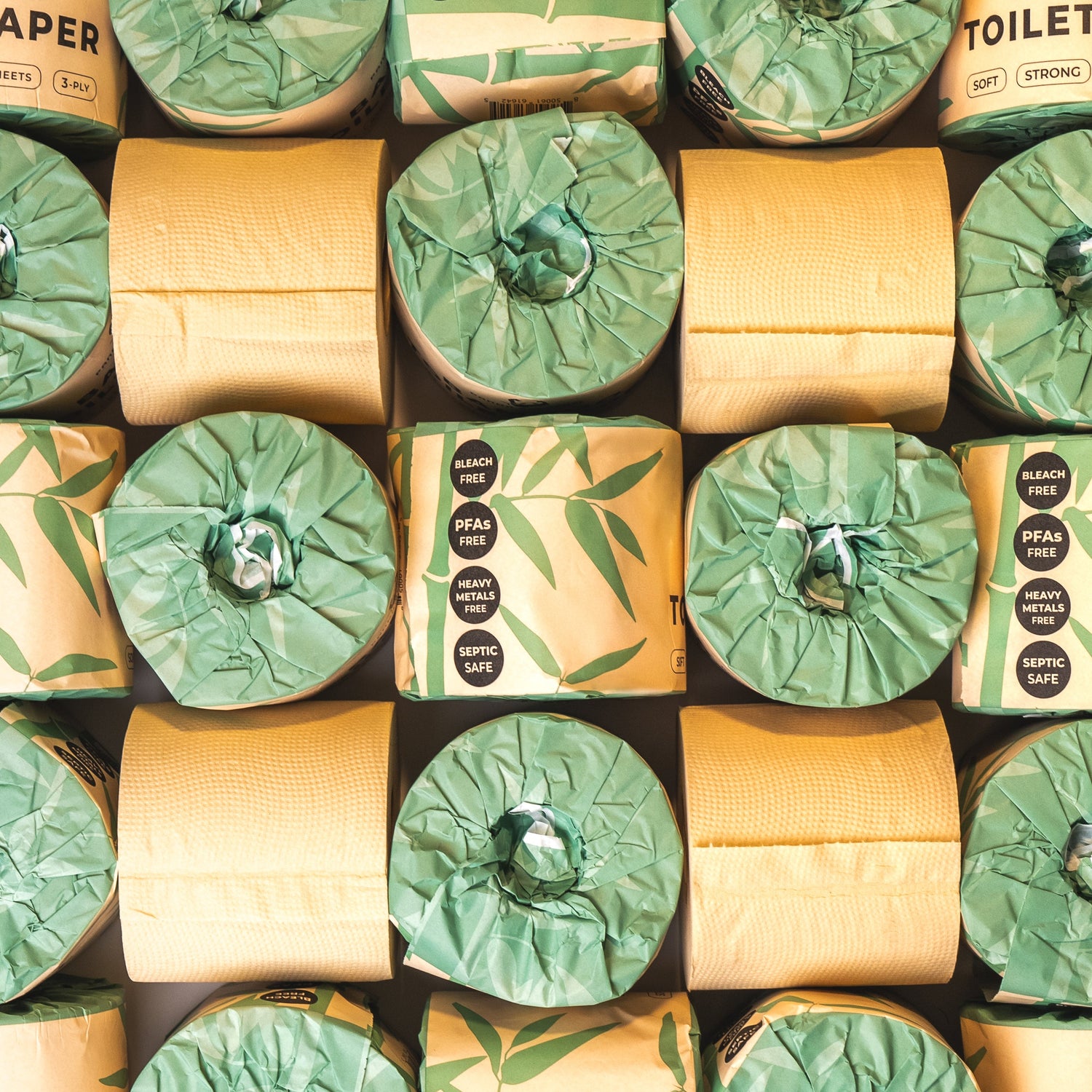 Pattern of green and beige Panda Eco Paper Bamboo Toilet Paper rolls with visible brand labels.
