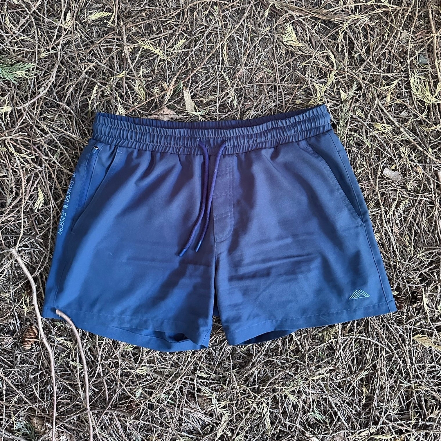 Athletic 5 Inch Recycled Shorts in Deep Navy by Rainier Watch with a drawstring on a textured brown ground