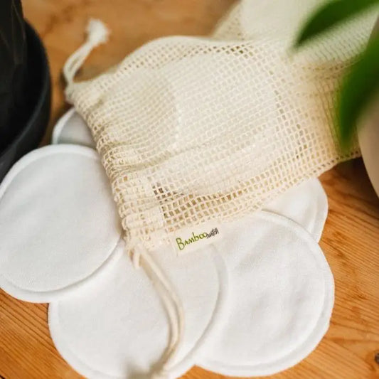 Set of 20 reusable facial rounds, made of bamboo, with a mesh storage bag on a wooden surface