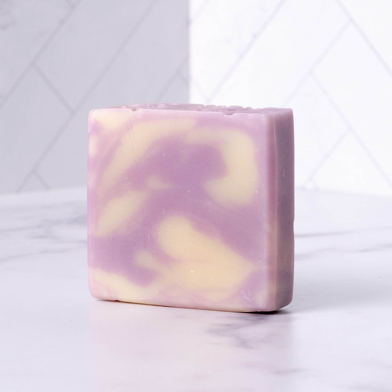Bar of lavender soap with purple and yellow swirls on a white background