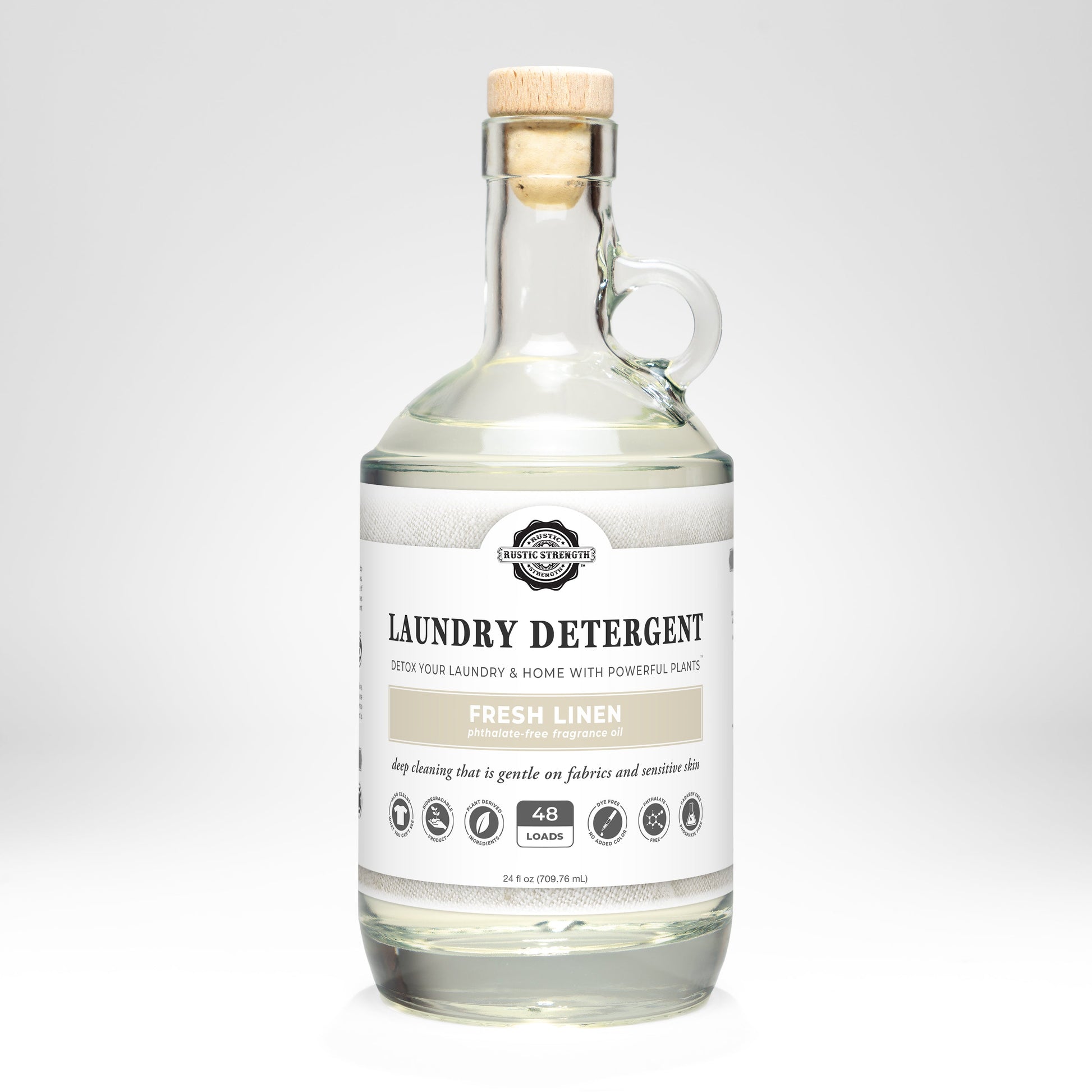 24oz glass bottle of Rustic Strength Liquid Laundry Detergent with a wooden cap on a white background