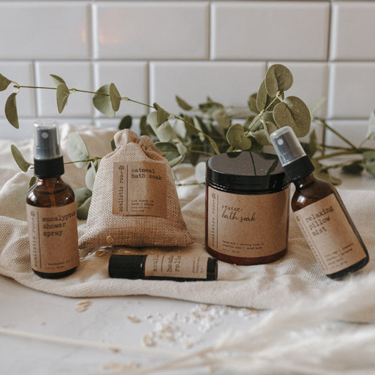 Spa Day Gift Set by Soulistic Root, products displayed with eucalyptus leaves on linen in a bathroom.