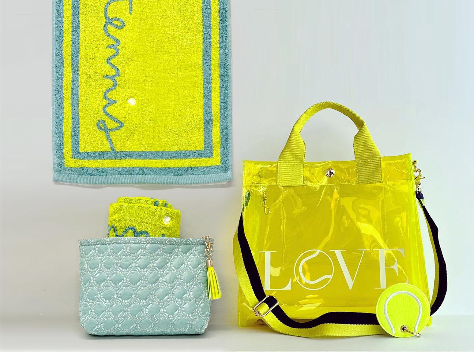 Clear event tote bag for concerts and sports, lightweight and durable. Yellow 'LOVE' bag with a tennis ball and turquoise quilted bag on a light gray background