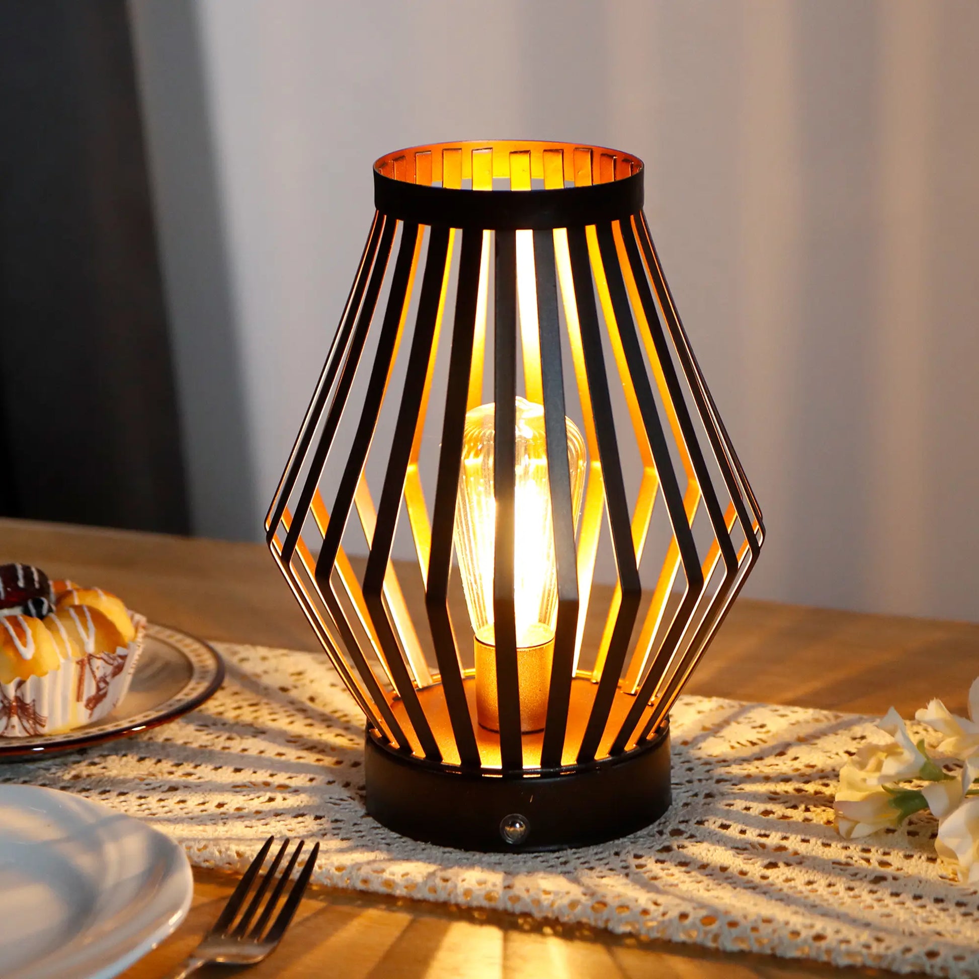 Decorative vintage-style table lamp with cage design on a table with food and cutlery