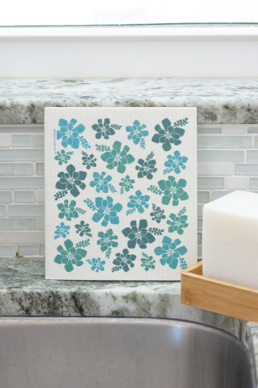 Floral-patterned dishcloth on a kitchen counter with soap and soap dish.