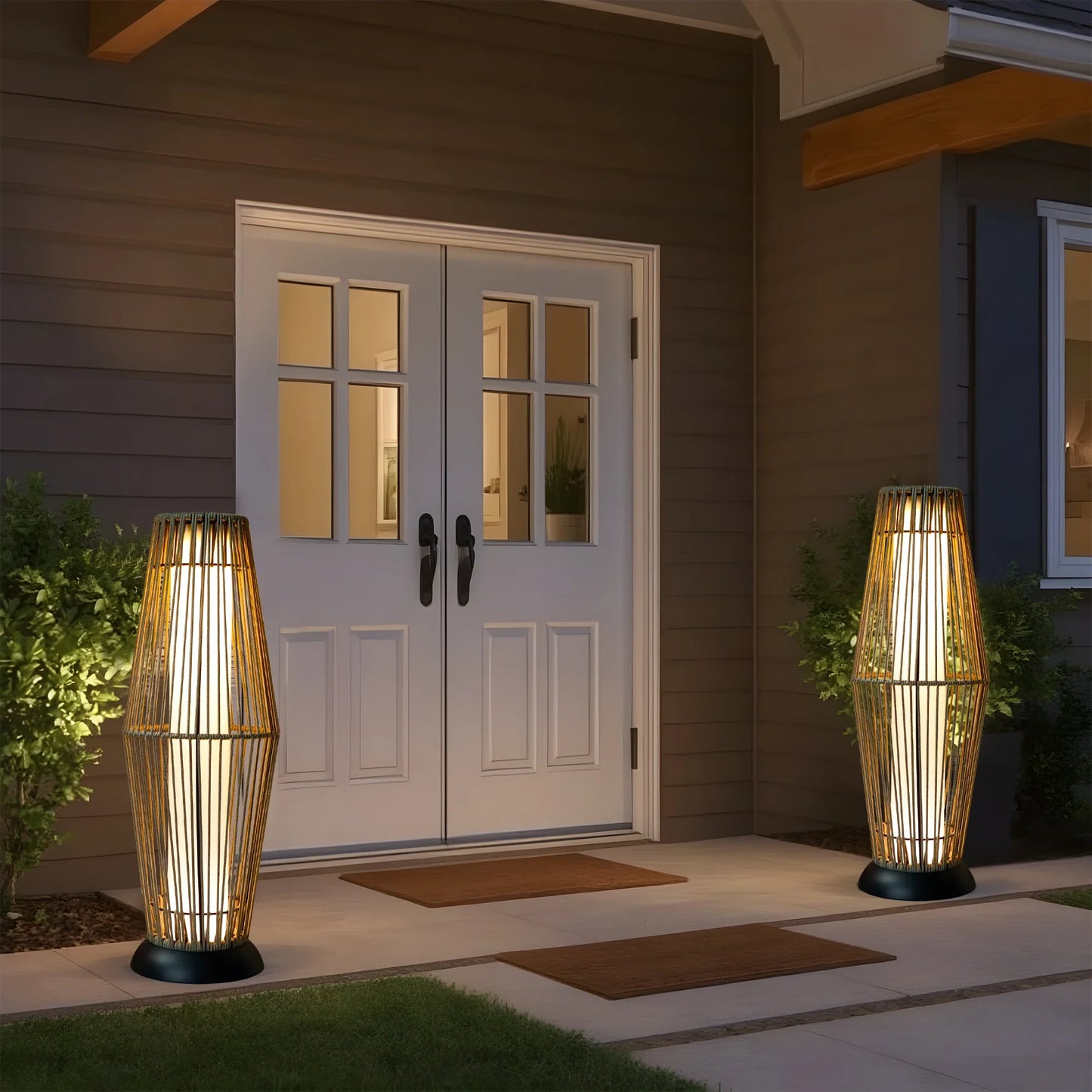 Two illuminated outdoor solar powered floor lamps on either side of a house entrance.